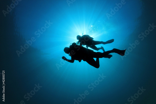 Two Scuba Divers silhouetted against sun