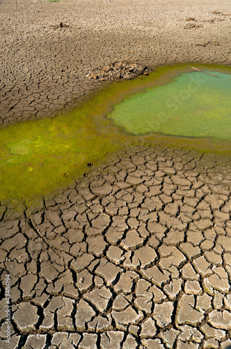 Polluted water and cracked soil of dried out lake during drought