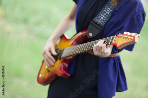 Close-up view at guitar in girl's hands at outdoor.