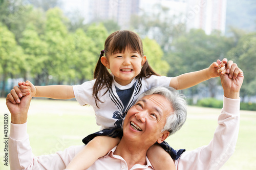 Chinese Grandfather Giving Granddaughter Ride On Shoulders