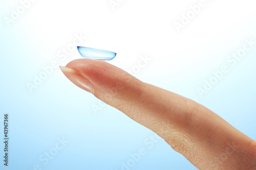 contact lens on finger on blue background