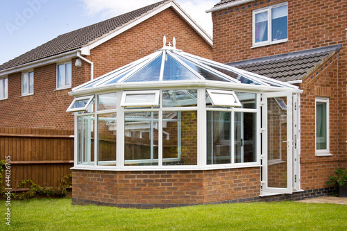 Conservatory with glass roof against a red brick house