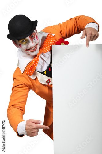Man dressed up as a joker pointing to a board for your image