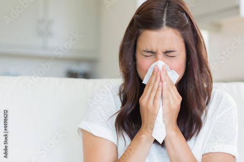 Brunette sneezing in a tissue