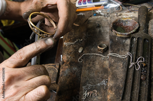 Goldsmith working on a bracelet with his aged hands