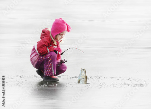 Little child fishing on a frozen lake in winter.