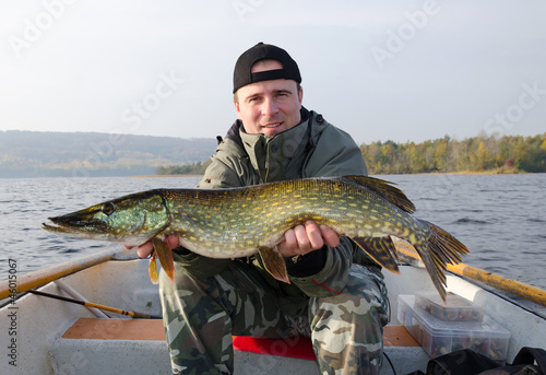 Happy angler with pike fishing trophy