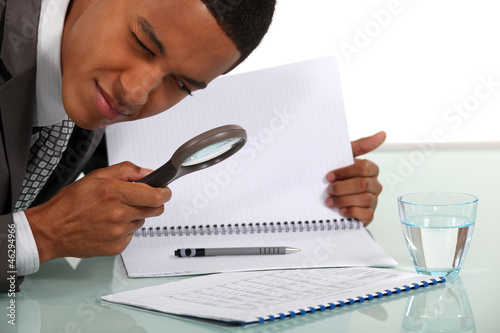 Man examining a document with a magnifying glass