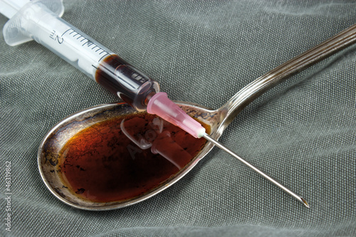 Drug syringe and cooked heroin on spoon