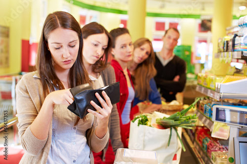 Frau sucht Geld an Supermarktkasse