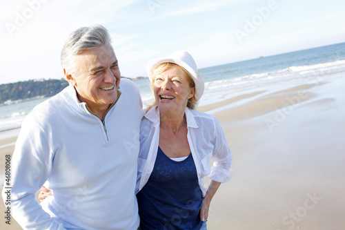 Senior couple walking on the beach in fall season