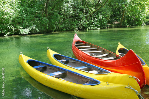 Four empty plastic canoes in turquoise green river