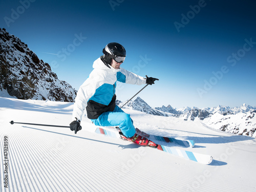 Skier in mountains, prepared piste and sunny day