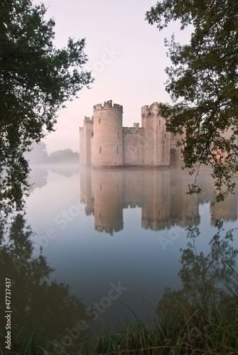 Stunning moat and castle in Autumn Fall sunrise with mist over m