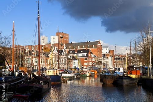 sunny canal in Groningen with many river boats