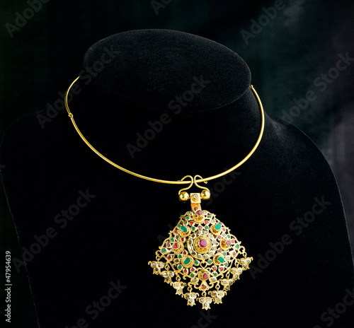 golden necklace with pendant decorated by gemstone