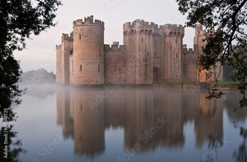 Stunning moat and castle in Autumn Fall sunrise with mist over m