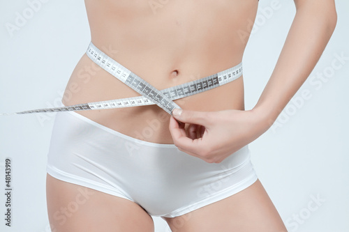 femme mesurant son ventre plat en boxer blanc