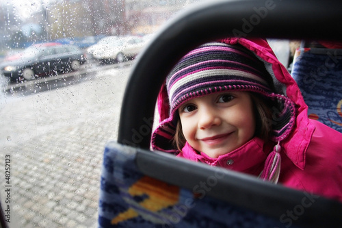 Uśmiechnięta dziewczynka jedzie autobusem