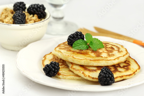 Fluffy pancakes topped with honey, blackberries and fresh mint