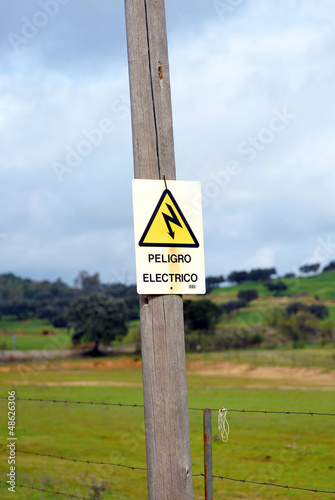 Poste eléctrico de madera con señal de peligro