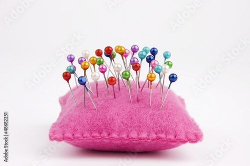 Handmade felt pin cushion with multicolored sewing pins stuck in