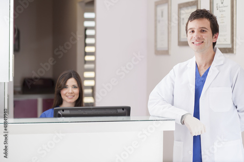 Male dentist and assistant greeting patients at the front desk