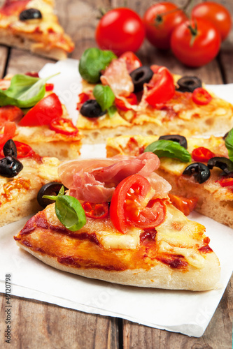 Pizza with ham, pepper and olives on old wooden background