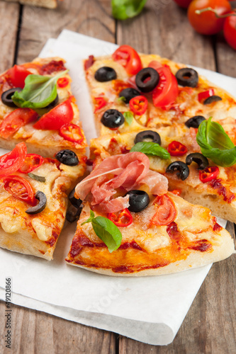 Pizza with ham, pepper and olives on old wooden background