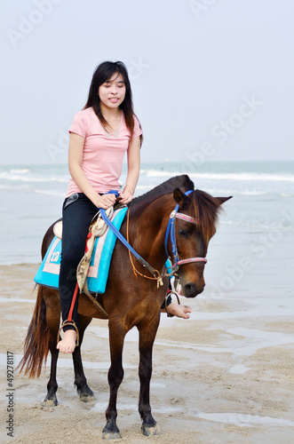beautiful asian woman with brown horse on beach