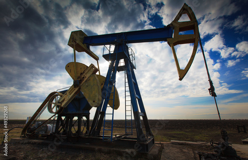 Operating oil well profiled on dramatic cloudy sky