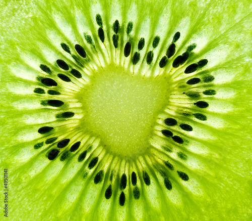 Gros plan rapproché d'une tranche de kiwi avec la chair et les pépins, macro de fruit exotique en hiver, arrière-plan vert, vitamines et alimentation, nutrition et santé