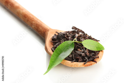 Dry black tea with green leaves in wooden spoon, isolated