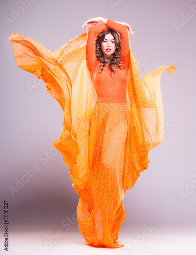 beautiful woman in long orange dress posing dynamic