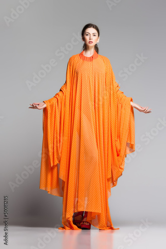 beautiful woman in long orange dress posing in the studio