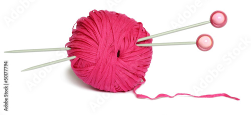 Pelote de fil de cotton couleur rose avec des aiguilles à tricoter isolée sur blanc.