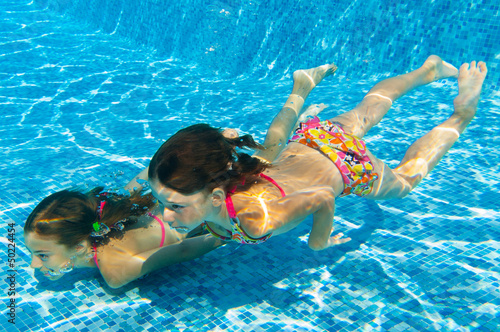 Underwater kids in swimming pool, girls swim and having fun