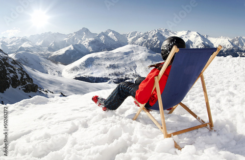 Women at mountains in winter lies on sun-lounger