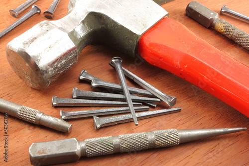 Box nails, hammer, and nail sets arranged on wood back ground