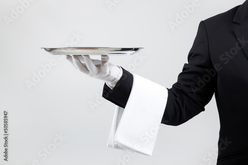 Waiter holding empty silver tray over gray background