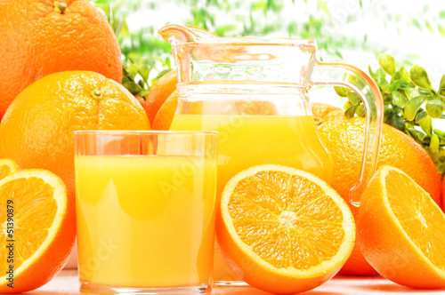 Glass and jug of orange juice and fruits