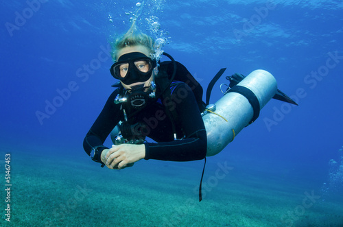 young atractive girl scuba dives in clear blue water