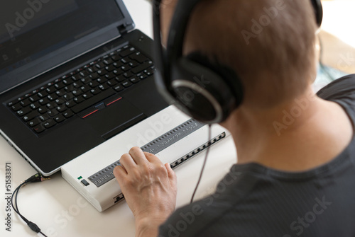 Blind person working on computer with braille display and screen