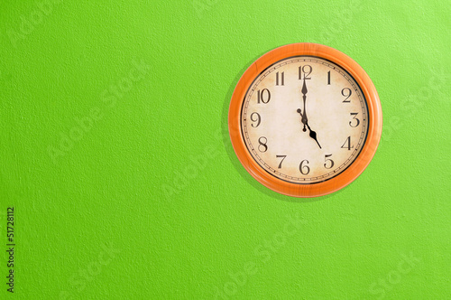 Clock showing 5 o'clock on a green wall