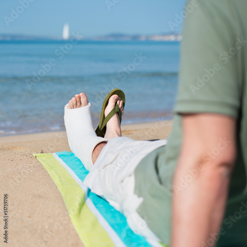 mann mit gipsfuß am strand
