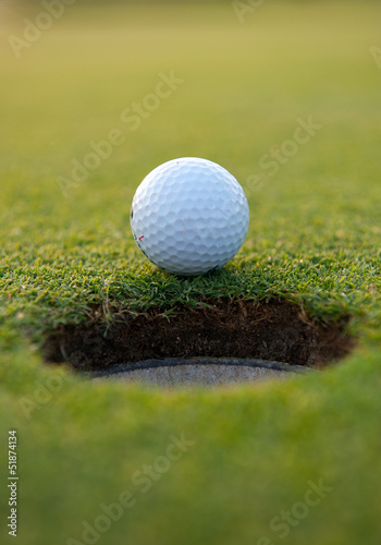 Golf ball by the hole