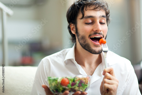 Man eating a salad on the sofa