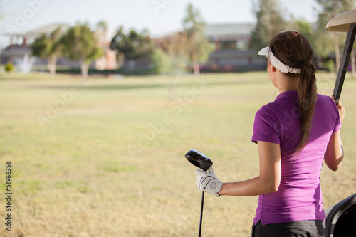 Young female golfer looking at the golf course with copy space