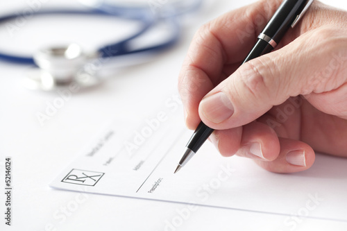 Doctor writing a prescription on Rx form in the consulting room