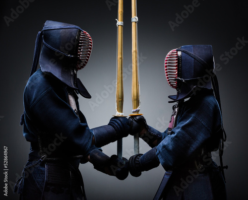 Two kendo fighters with shinai opposite each other